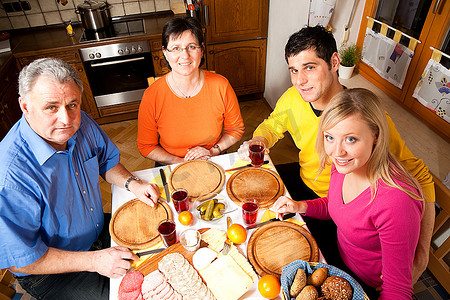 一家人与成年子女共进晚餐，有面包、冷盘和奶酪