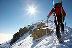男子滑雪攀登者攀登积雪的山脊；水平体格。意大利阿尔卑斯山。