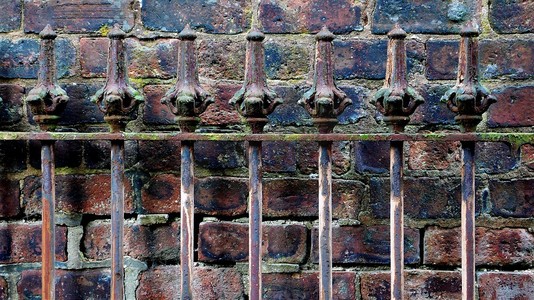 旧铁杆栅栏贴着砖墙的细节。