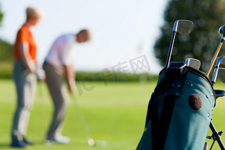 成熟或高级夫妇打高尔夫球，重点是在前面的袋子