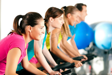 四人一组在健身房里旋转，锻炼他们的腿做有氧训练