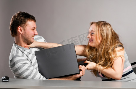 使用权摄影照片_一对微笑的夫妇正在为他们共同的笔记本电脑的使用权而战
