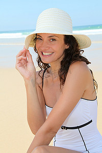 海滩美女摄影照片_戴着草帽坐在海滩上的美女