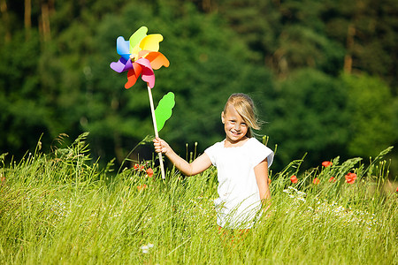 田野里的小女孩在玩五颜六色的风车玩具