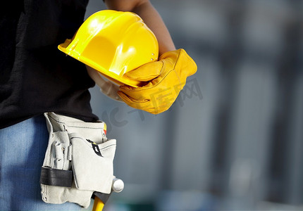建筑工地上戴着黄色头盔和工作手套的建筑工人