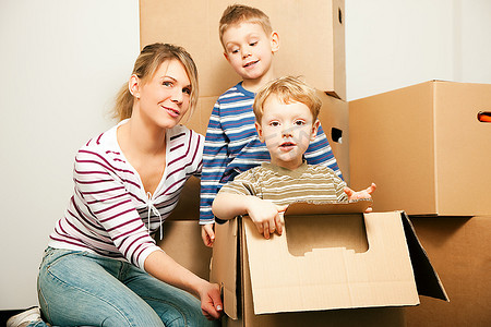 一家人搬进了新房子。儿子们都坐在移动的箱子里，每个人都显得很高兴