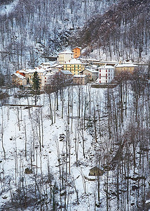 房屋山摄影照片_冬天的小山村。垂直框架。意大利阿尔卑斯山，欧洲。