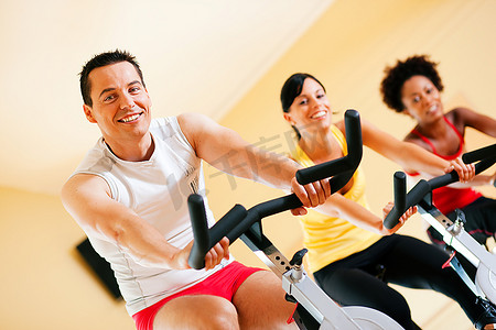 三人一组--想必是朋友--在健身房里旋转，锻炼腿部运动和有氧运动