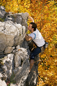 一名男子在攀登山顶前攀登了一块岩石
