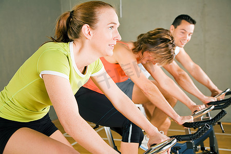 三个人在健身房的固定自行车上锻炼