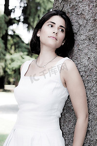拉丁文摄影照片_一位年轻的拉丁女孩的垂直肖像，黑发，穿着白色衣服