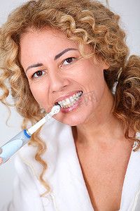 肖像妇女使用电动牙刷