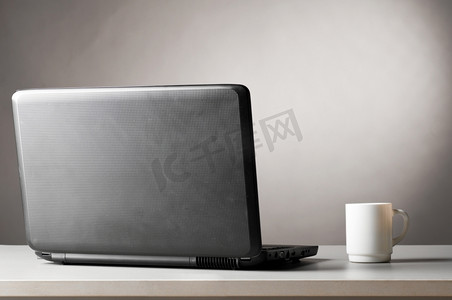 一杯热咖啡摄影照片_桌上有笔记本电脑和一杯热咖啡