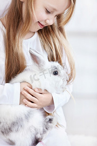 美丽的小女孩抱着一只滑稽的兔子