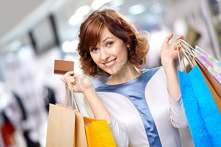 肖像年轻美丽的女人微笑在商店用袋子和信用卡