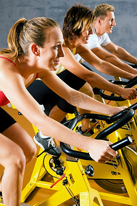 三个人骑着自行车在健身房或健身俱乐部锻炼