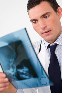 一名男医生在检查人体头骨的X光片
