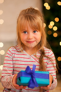 圣诞树前拿着礼物的女孩