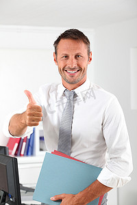 老板办公室摄影照片_在办公室竖起大拇指的快乐商人