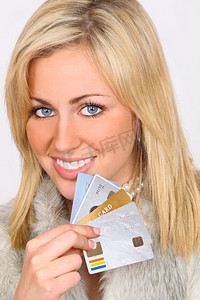 一位年轻漂亮的金发女子穿着(假的)皮草，手里拿着一张信用卡