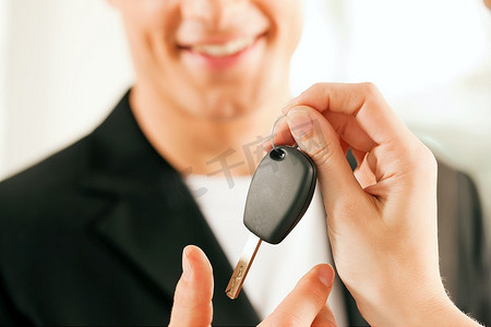 一名男子在一家汽车经销商购买一辆汽车，女销售代表给了他钥匙，微距镜头聚焦在手和钥匙上