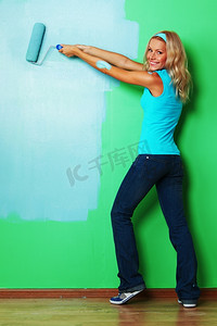 一名女子在墙面上画滚筒