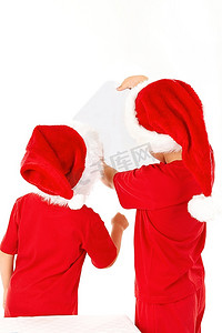 两个戴着圣诞老人帽子的小男孩的背影，孤立地看着床单