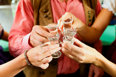 白酒婚宴摄影照片_巴伐利亚特拉赫特的人们在酒吧里用烈酒碰杯
