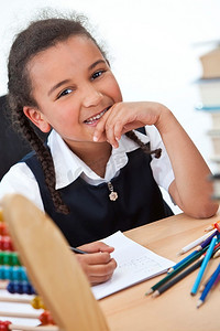 一个年轻漂亮的混血女孩在被书和算盘包围的学校教室里写作