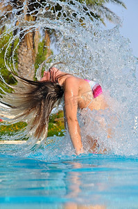 惊艳艺术字摄影照片_苗条的女人惊艳地跳出泳池，抖动着头发