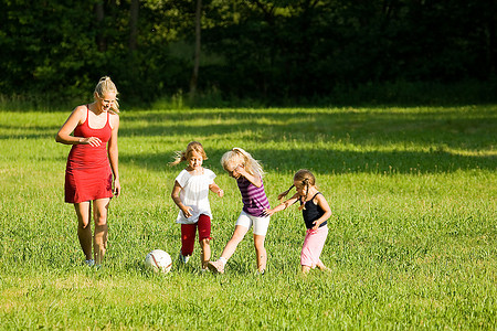 幸福的一家人在阳光明媚的绿色草地上踢足球(对北美来说是足球)