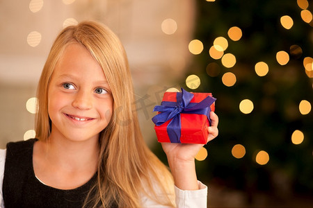 圣诞树前拿着礼物的女孩