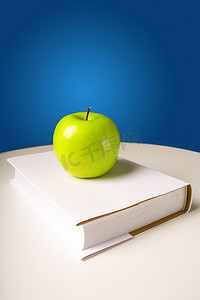 书籍上的苹果摄影照片_绿色闪闪发光的苹果放在书上