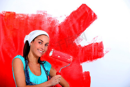 一名年轻女子把房子的墙壁漆成红色