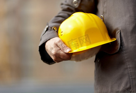 戴着黄色安全帽的建设者之手，自然光，选择性聚焦