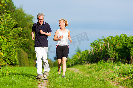 成熟或年长的夫妇在户外运动，夏天在小路上慢跑