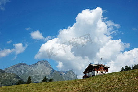 意大利阿尔卑斯山中的小屋；背景是多岩石的山峰，多云的天空；夏天。