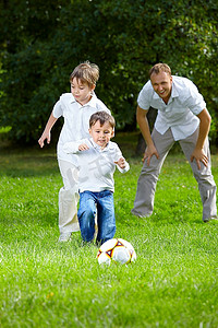 两个小兄弟在夏日花园里踢足球