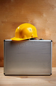 木质背景下的黄色安全帽和金属工具箱