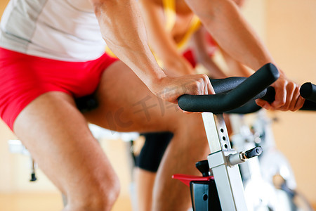 三个人在健身房里旋转，锻炼他们的腿和心脏训练，只看到四肢和轮子