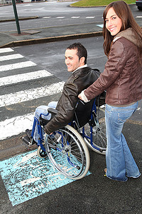 穿越马路摄影照片_妇女帮助朋友在轮椅上过马路