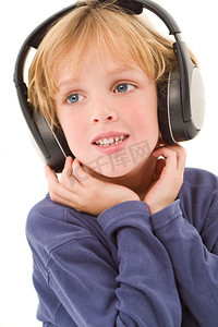 倾听孩子的声音摄影照片_演播室拍摄了一个年轻的金发男孩戴着耳机听音乐