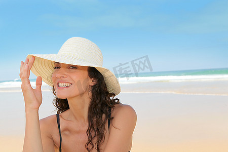 戴着草帽坐在海滩上的美女