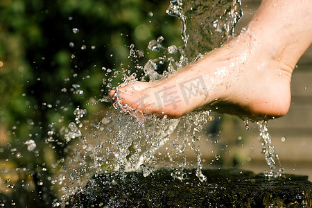 光照疗法摄影照片_在水疗的替代疗法中，冷水洒在脚上；冰冻的水滴