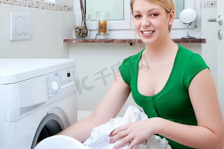 杂务摄影照片_使用洗衣机洗衣服的妇女