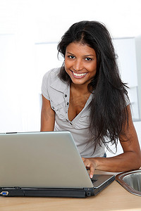 一名年轻的拉丁女子在家中厨房里使用笔记本电脑