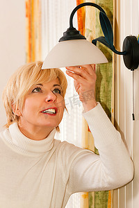 一名女子在公寓里的一盏灯里换灯泡