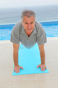一位老人在游泳池边锻炼身体