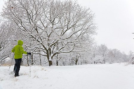 暴风雪期间，一名男子在冬季森林中穿着雪地鞋徒步旅行。水平框架。