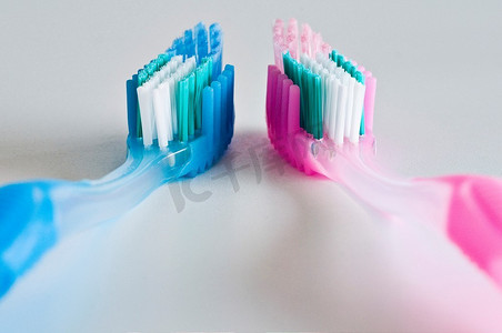 对立面摄影照片_将几把粉色和蓝色的牙刷面朝上并排放在一起。
